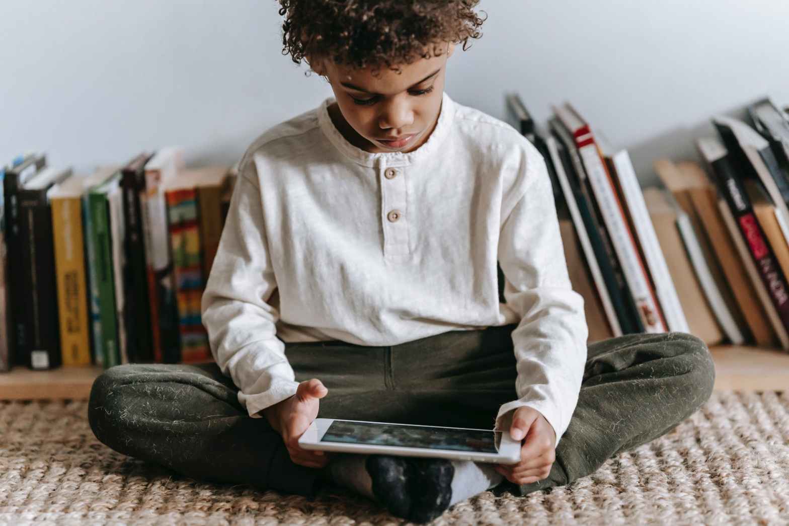 crop black boy browsing tablet in room