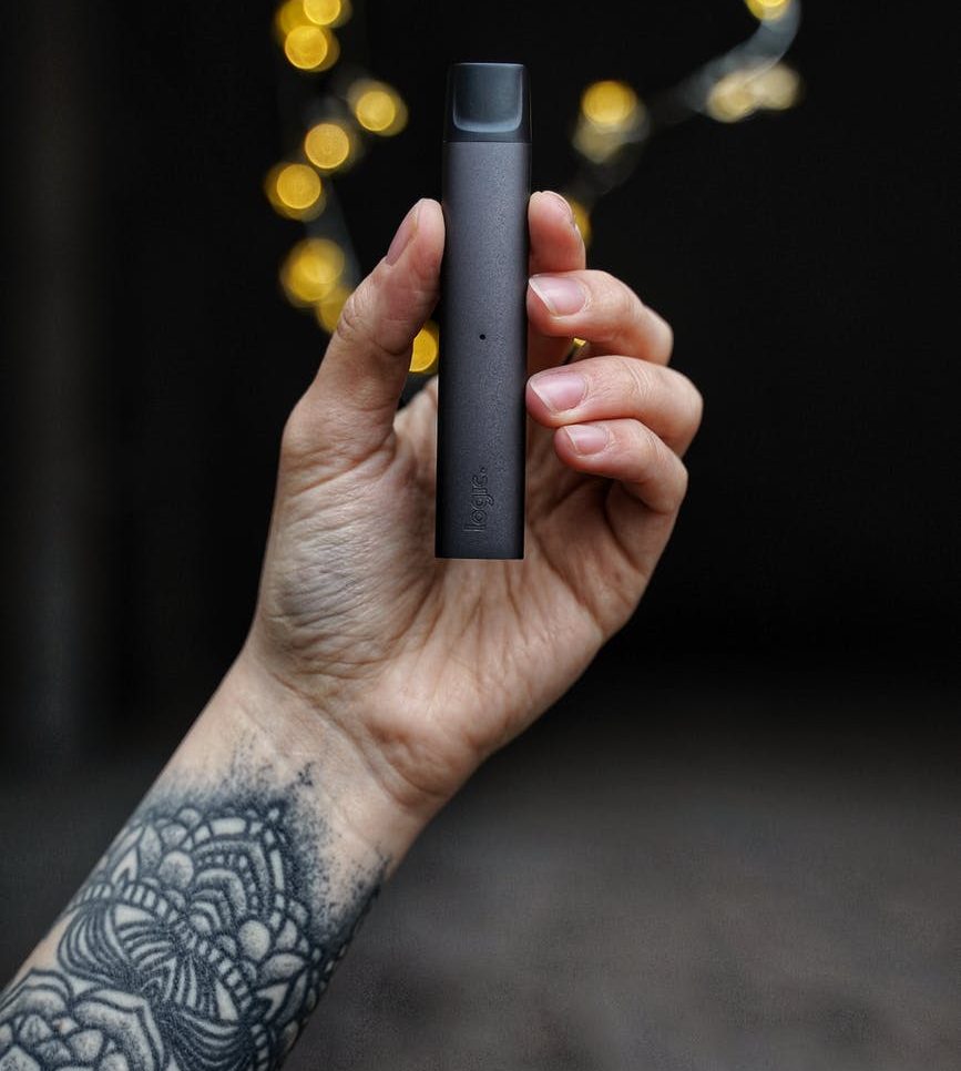 man with tattooed arm holding logic vape pen