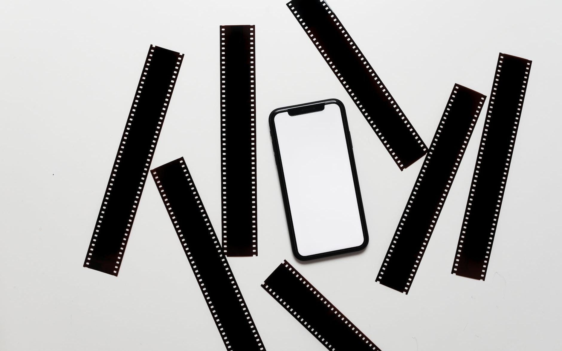 mobile phone with blank screen placed on table near scattered filmstrips